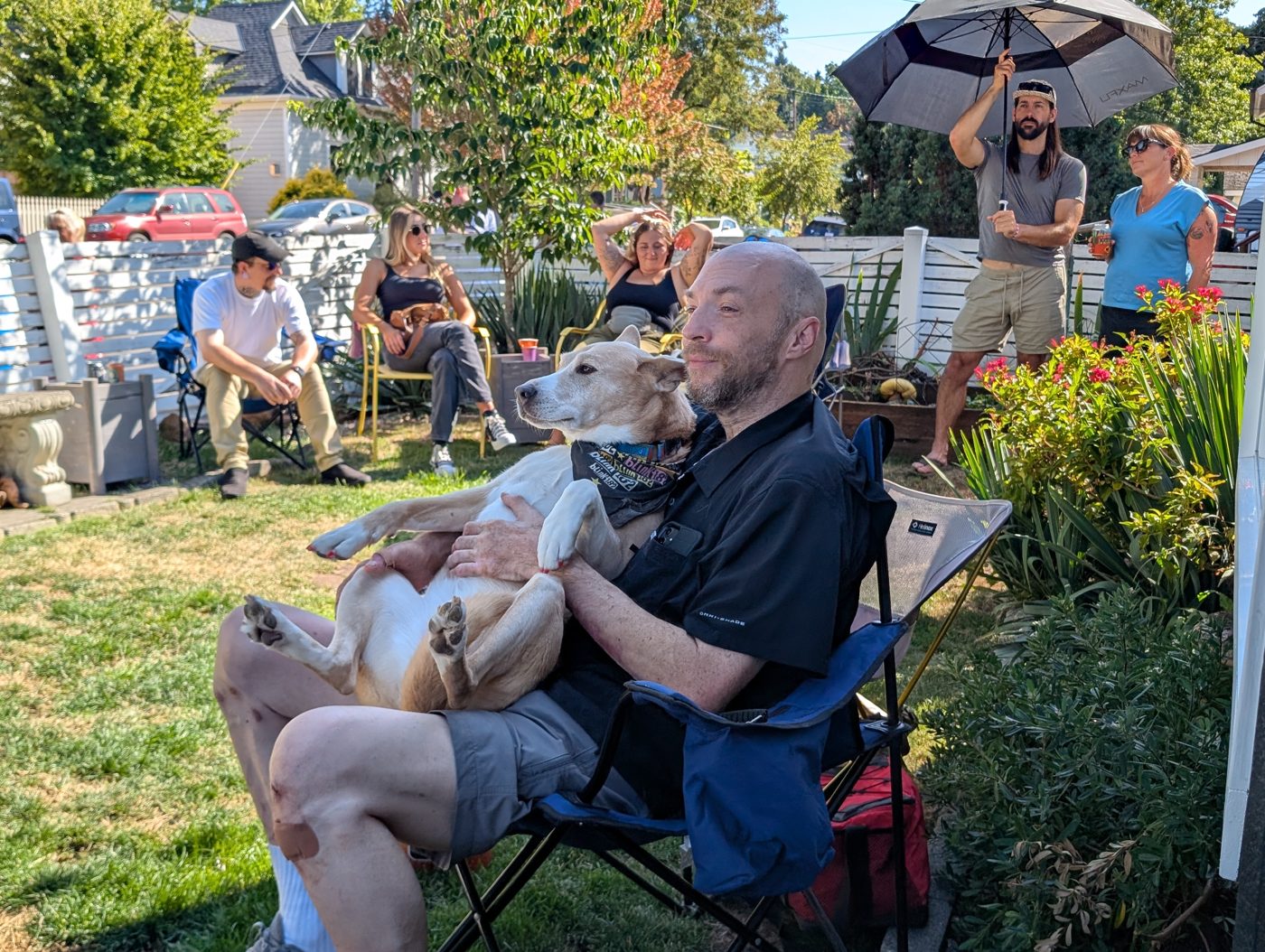 Festival goers relaxing in camp chairs with a dog