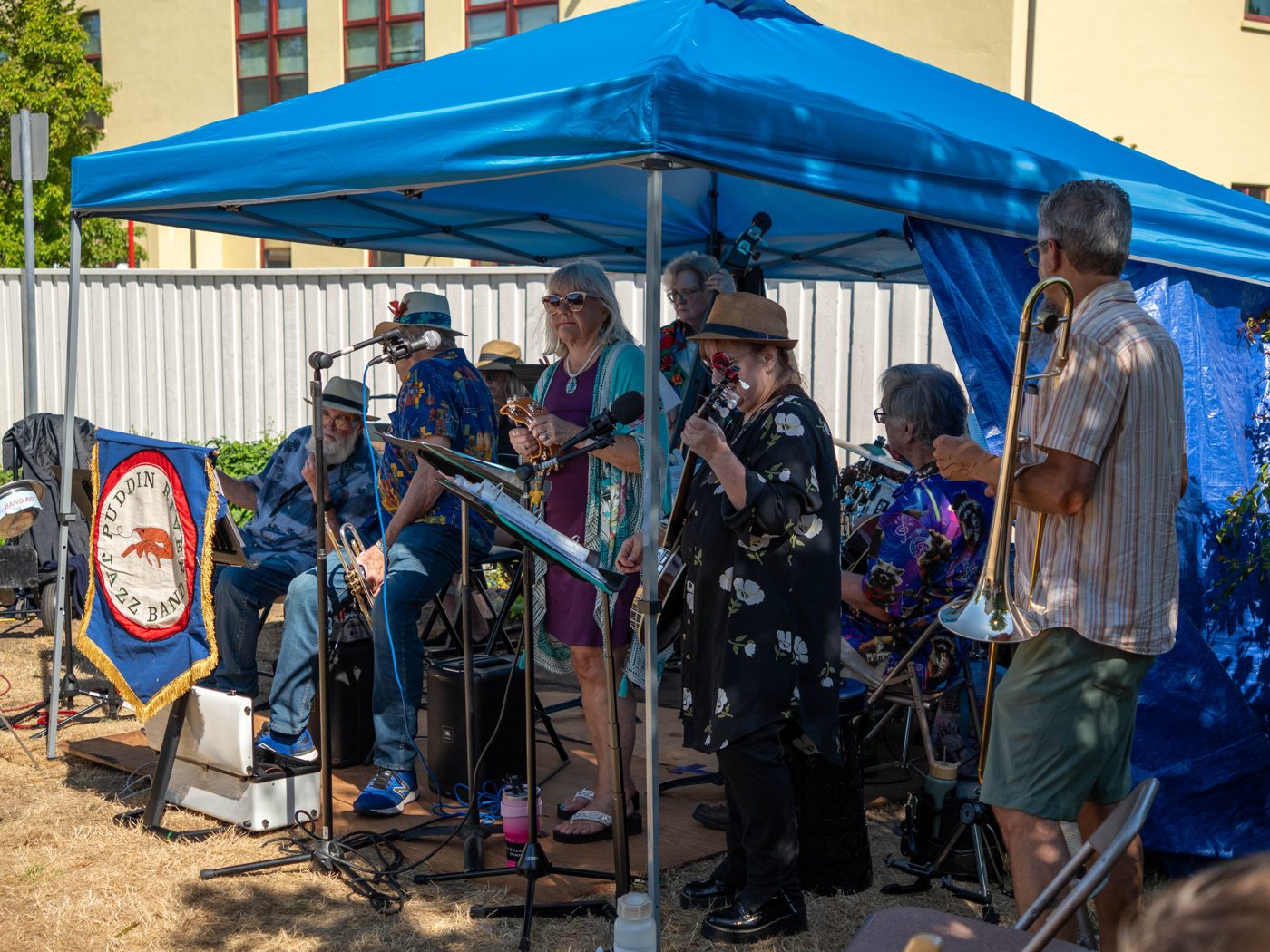 A band performing under a blue canopy on a sunny afternoon
