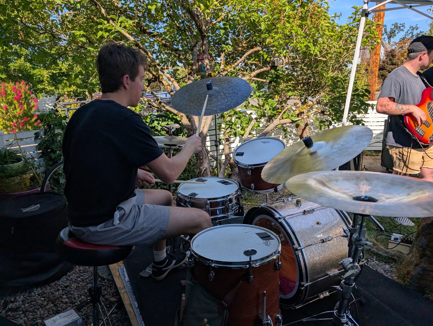 A drummer playing an outdoor kit at a porch concert